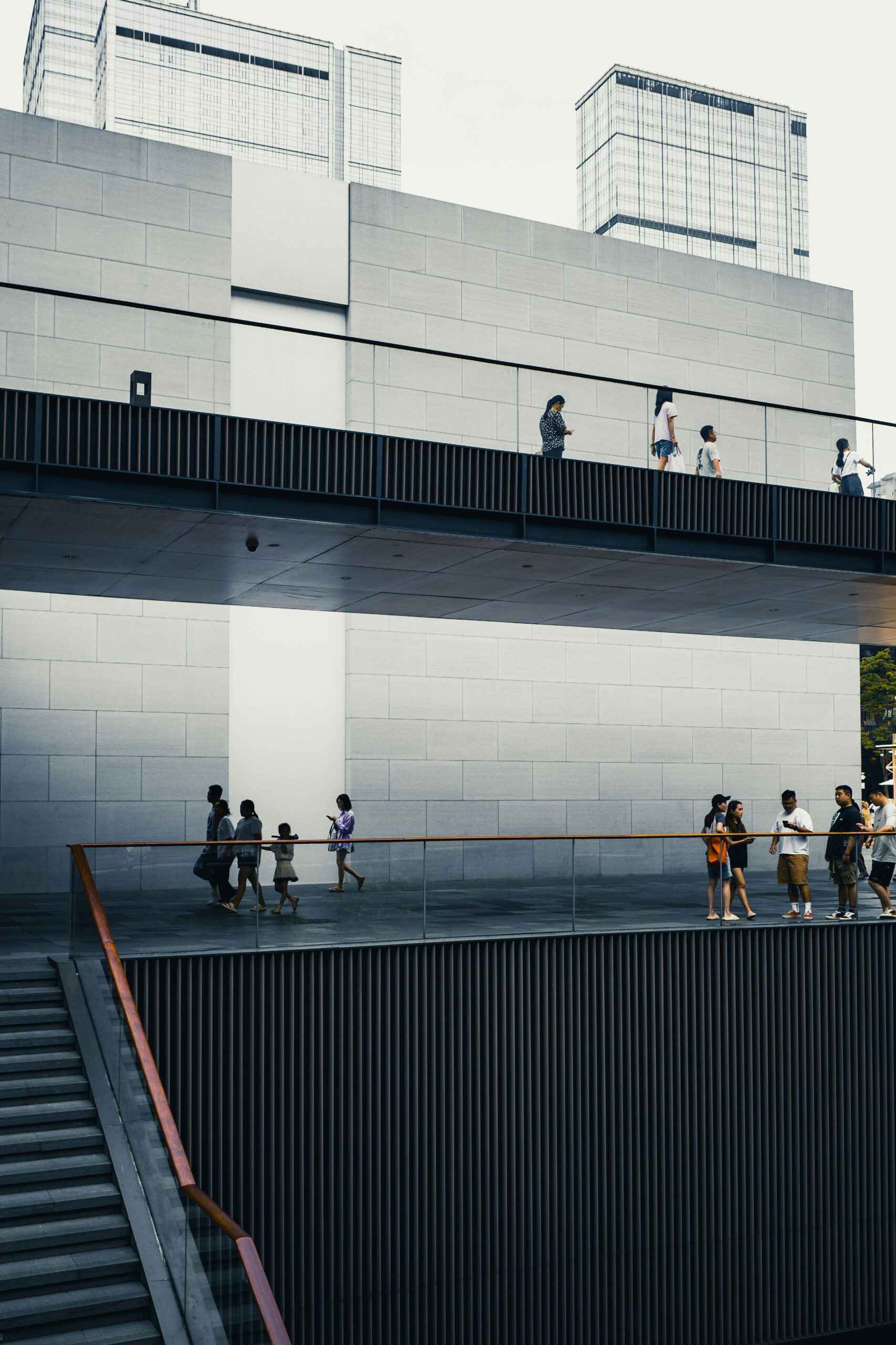 People captured from afar moving distractedly across a modern architectural complex